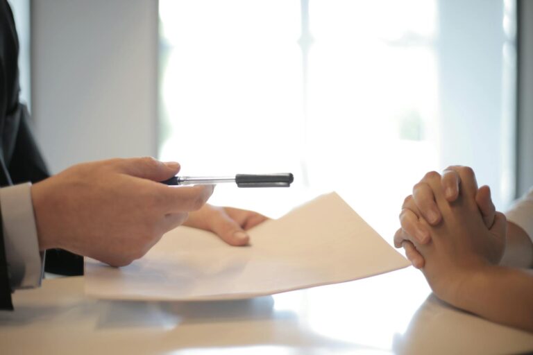 Close-up of a contract signing with hands over documents. Professional business interaction.