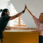 Young couple high-fiving in their new home, happily surrounded by moving boxes.