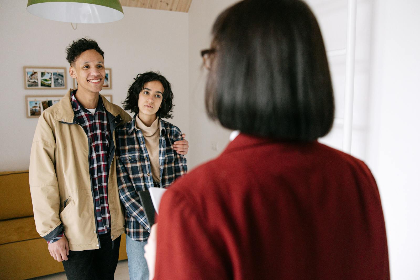 Young couple discussing real estate options with an agent indoors, highlighting home buying process.